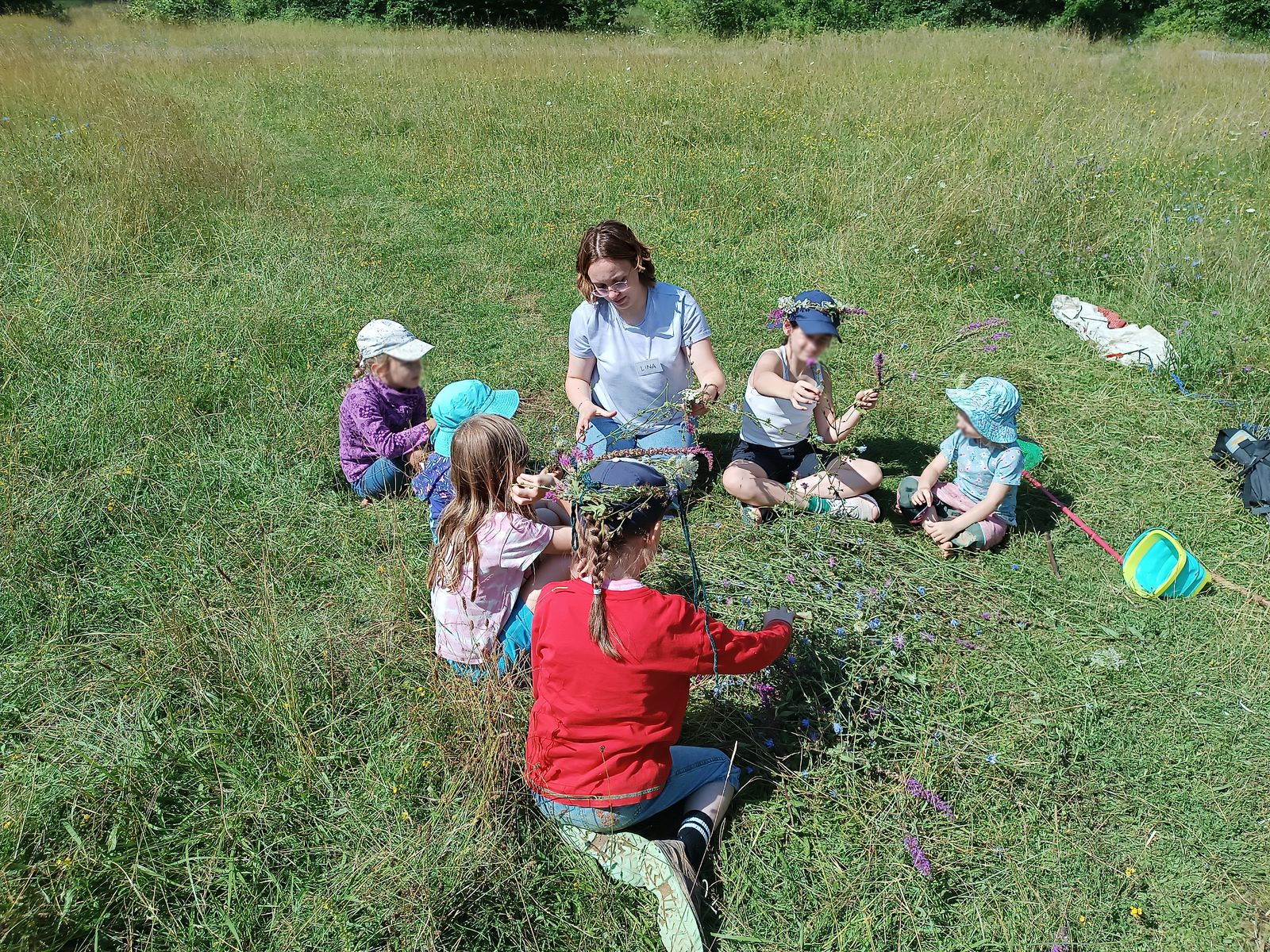 Kinder flechten gemeinsam mit Naturmaterialien während der Waldwoche im Bad Vilbeler Wald